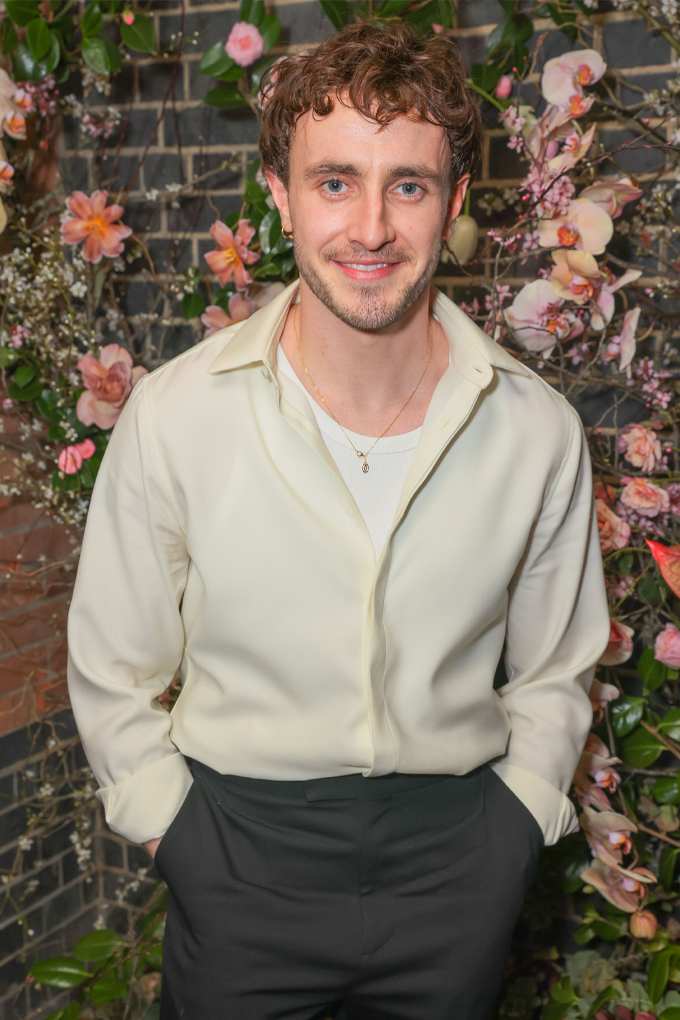 Paul Mescal in lässigem Outfit in Creme-Schwarz vor Blumenwand