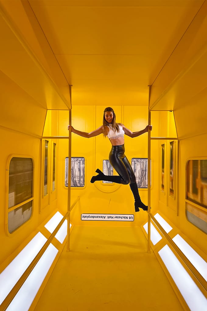 Stella Stegmann posiert im Studio of Wonders zwischen zwei Haltestangen in einem stilisierten Bahnwagon