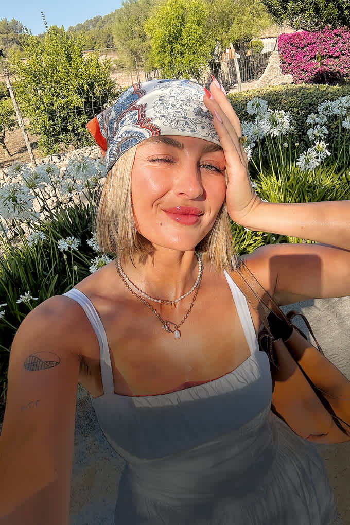 Influencerin Sophie Berna sitzt bei strahlender Sonne auf einer Blumenwiese