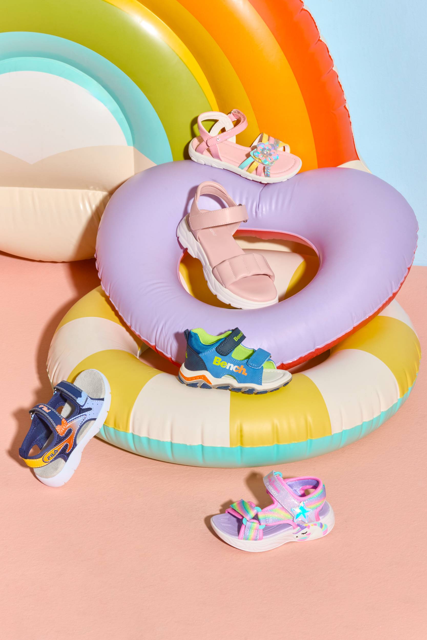 Zwei bunte Schwimmringe übereinander, umgeben von Kinder-Sandalen