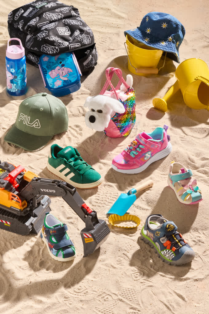 Kinderschuhe und Spielzeug, liegend auf einer Sandfläche