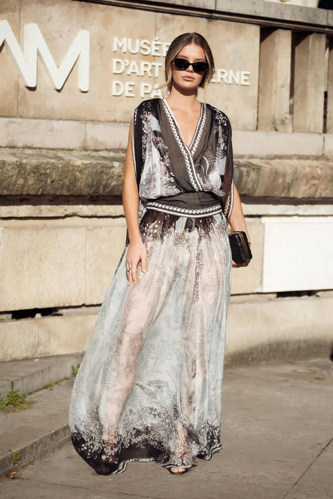 Frau mit Sonnenbrille, präsentiert sich elegant in durchsichtigem Gaze-Outfit