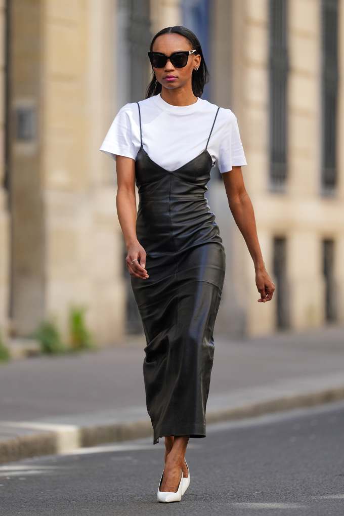 Frau trägt schwarzen Slip-Dress, gestylt mit weißem T-Shirt für den Y2K-Style