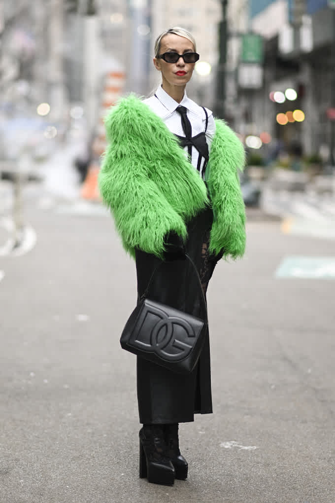 Frau in Corporate Look, kombiniert mit Fake-Fur-Mantei in Neongrün