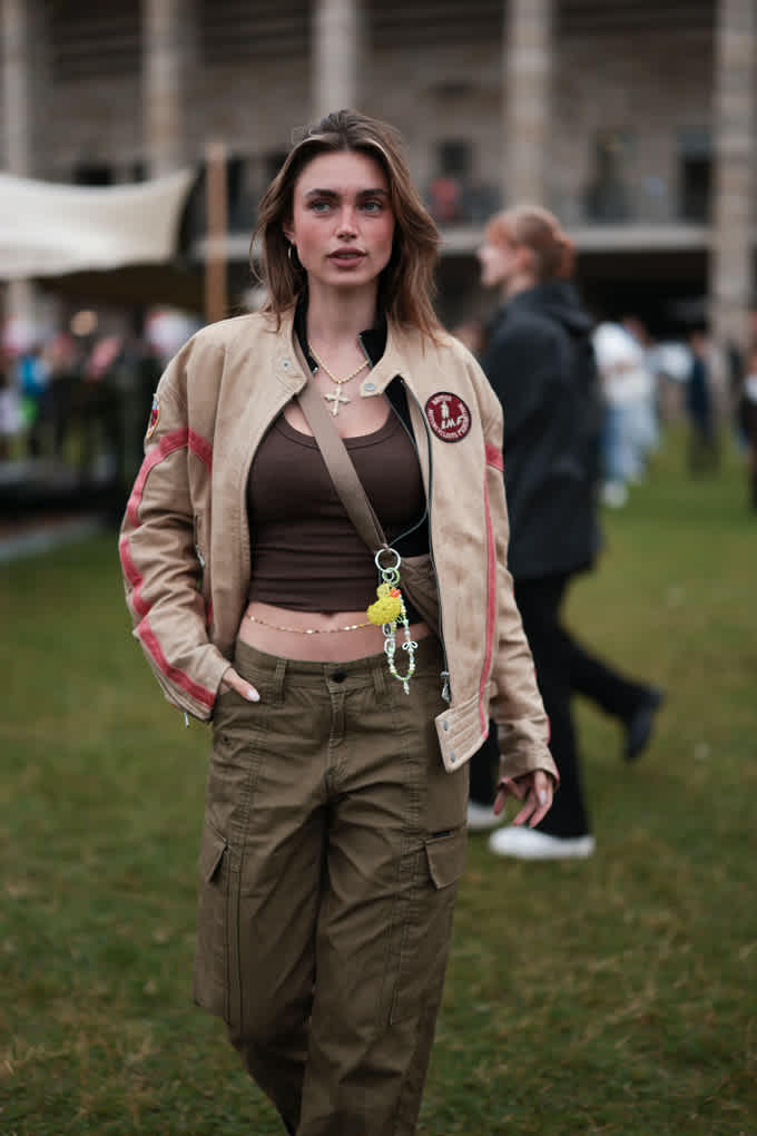 Frau mit Racing-Jacke, schwarzem Croptop und Loose-Fit-Cargopants