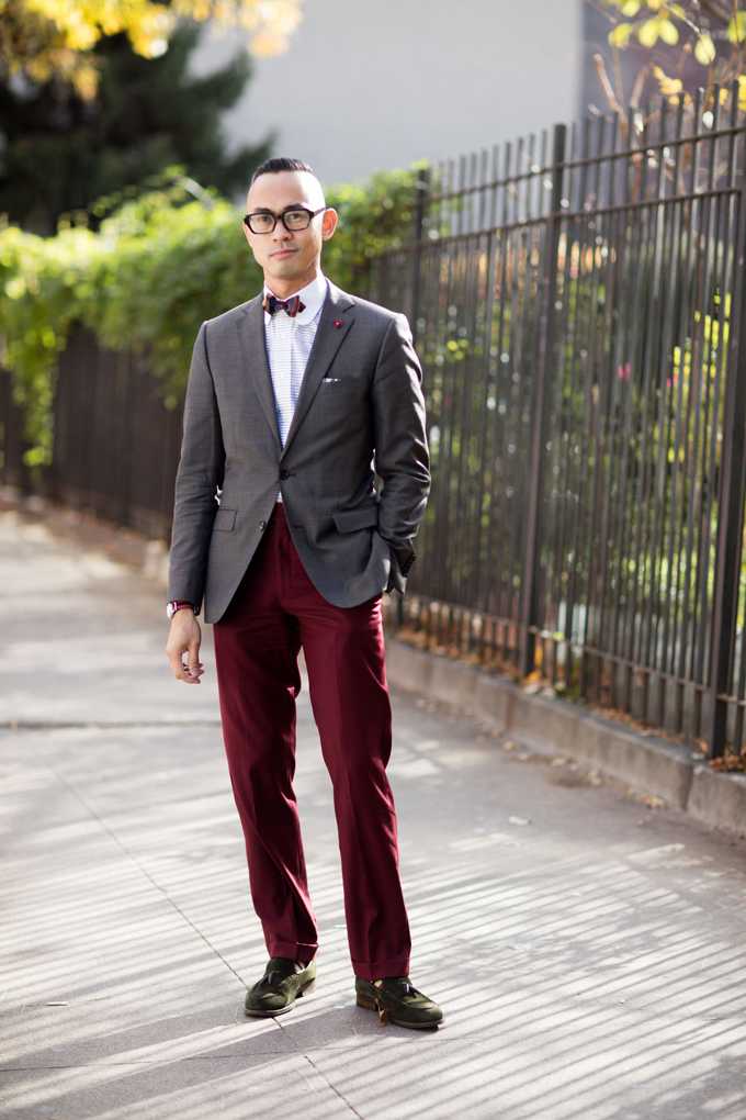 Ein Mann trägt einen dunkelgrauen Blazer mit einer roten Fliege und einer dunkelroten Anzugshose