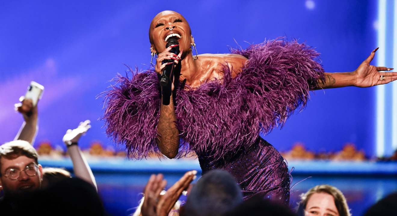 Sängerin Cynthia Erivo in einem lila Kleid, steht singend auf einer Bühne