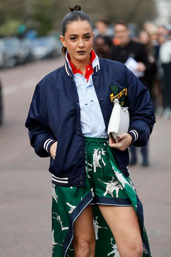 Frau in Varsity-Blouson im Layering-Stil, kombiniert mit Hemd, Poloshirt und Rock