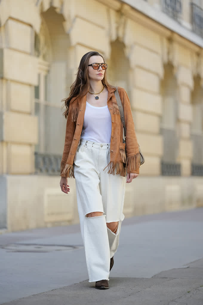 Frau trägt cognacfarbenes Shacket mit weißem Top und High-Waist-Jeans mit Cut-Outs