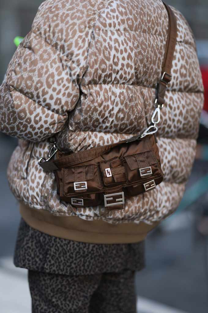 Frau mit Fake Fur-Mantel im Animalprint-Look trägt Handtasche auf dem Rücken