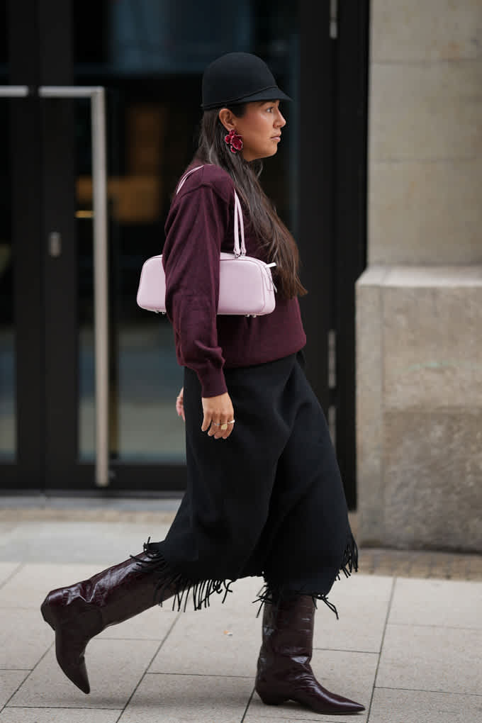 Frau trägt schwarzen Wollrock und tiefrote Jacke, kombiniert mit Baguette Bag in Pastellrosa
