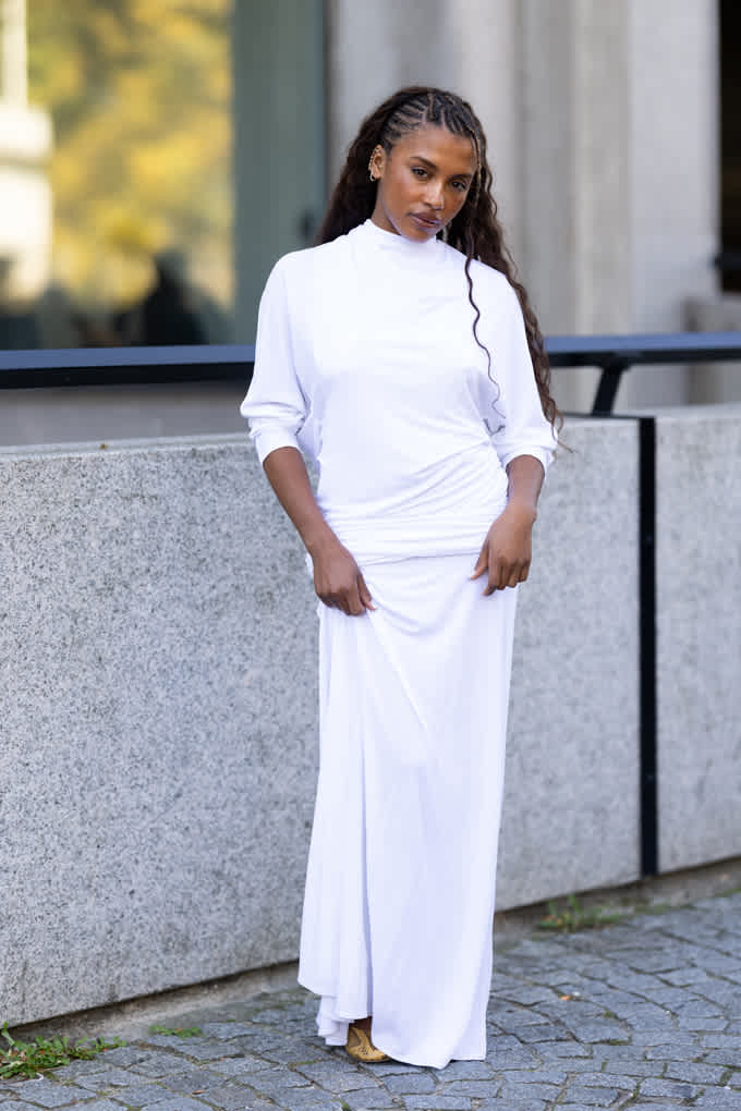 Dunkelhäutige Frau mit schwarzen Haaren in reinweißem Outfit