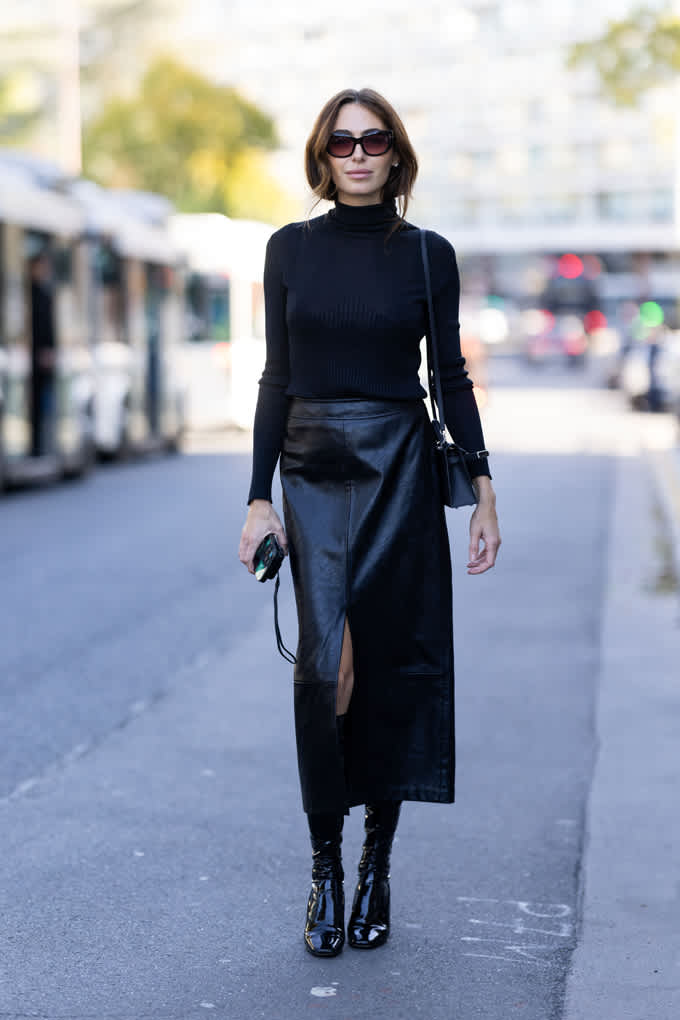 Schlanke Frau mit schwarzem Rollkragenpullover und Midi-Lederrock