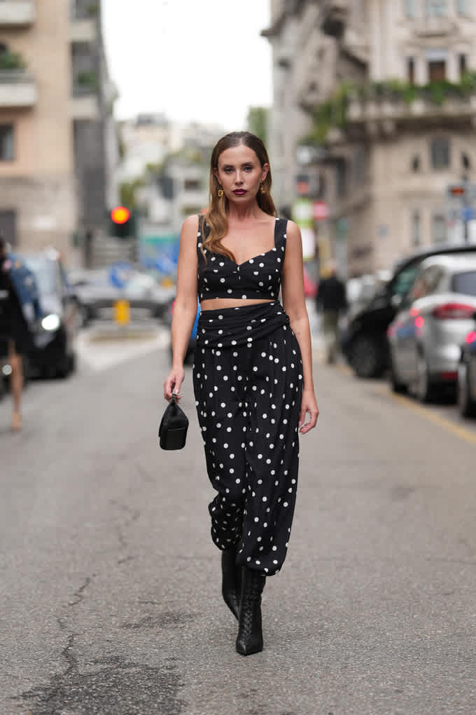 Frau steht auf Straße, trägt Palazzo-Hose und Bustier im schwarz-weißen Polka Dots-Design