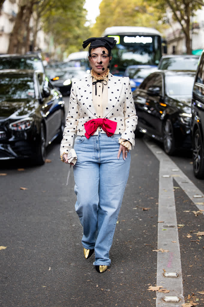 Frau spaziert in Bluse in Polka Dots-Design zwischen Autos entlang