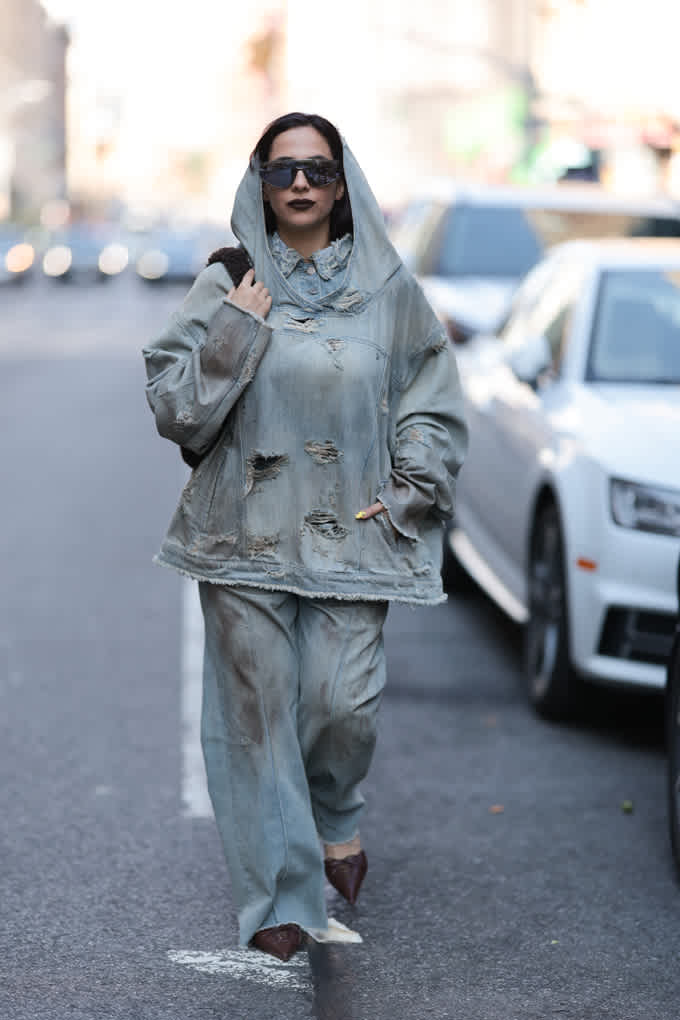 Frau spaziert auf Straße, trägt übergroße Kapuzenjacke mit Baggy Jeans