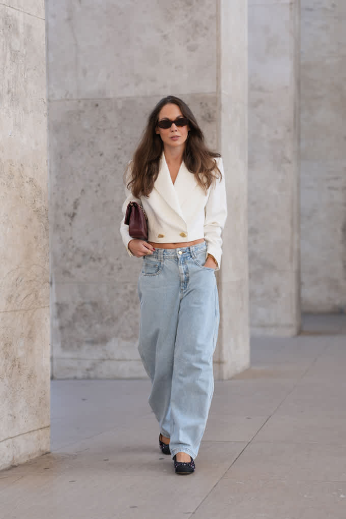 Brunette Frau trägt Cropped Double-Breasted-Blazer in Cloud-Weiß zu einer hellen Wide-Leg-Jeans. Clean mit Kante.