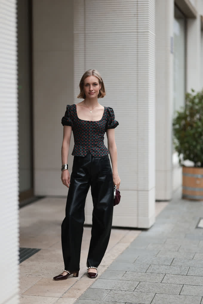 Junge Frau mit blonden Haaren, kombiniert schwarzes Puffärmel-Shirt mit glänzenden Barrel Pants