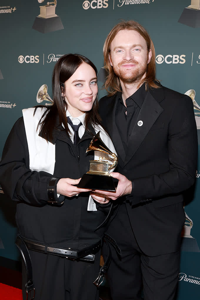 Zwei Personen posieren vor Logo-Wand bei den Grammys