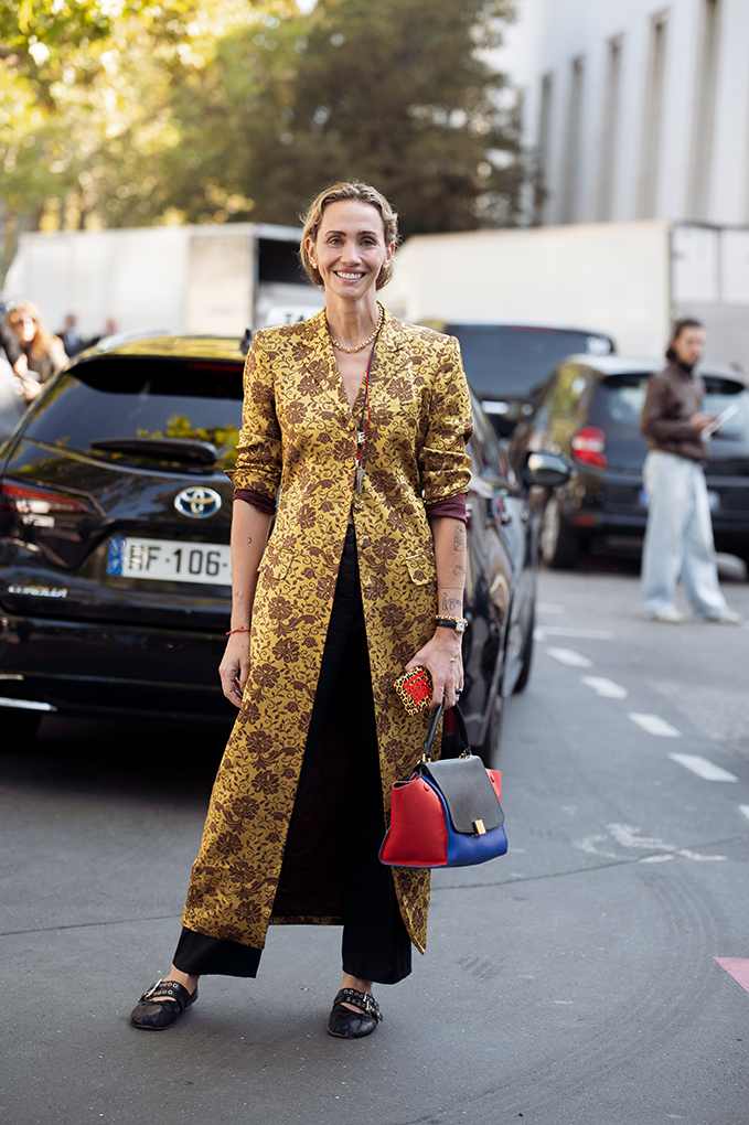 Frau steht auf Straße, trägt goldenen Jacquard-Longcoat