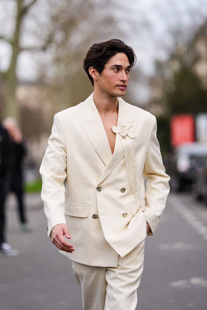 Mann spaziert in cremefarbenem Anzug mit Blüten-Applikation