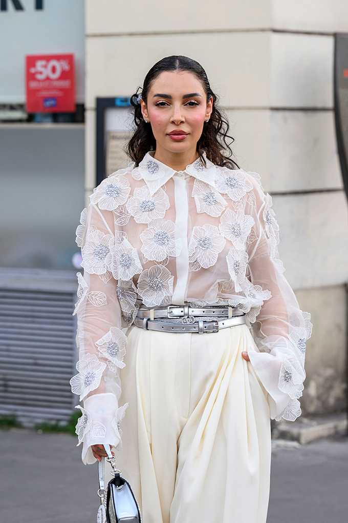 Frau trägt transparente weiße Bluse mit floralen Applikationen