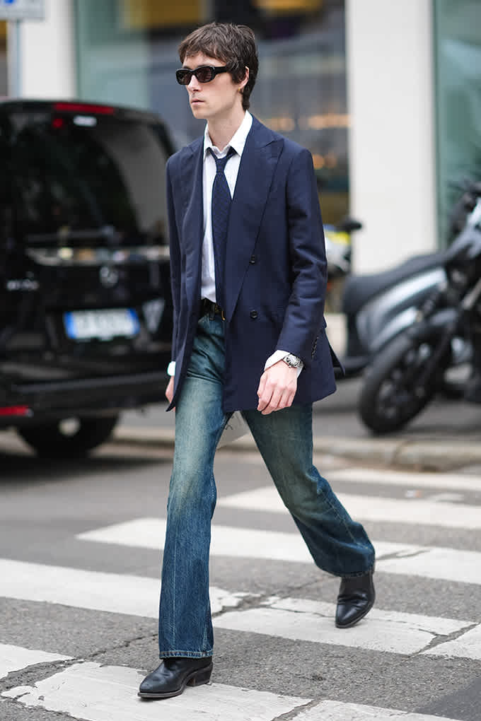 Mann auf Zebrastreifen, trägt Anzugjacke in Kombination mit ausgewaschener Jeanshose