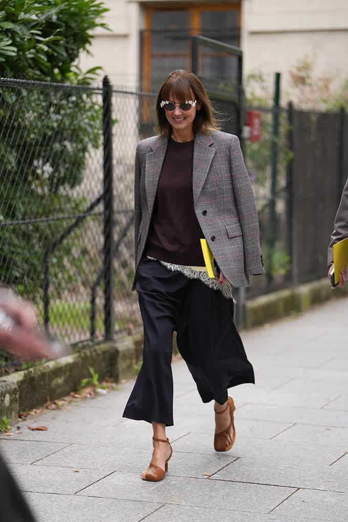 Frau auf Gehweg, trägt grauen Blazer mit schwarzem Sweater und passender Culotte