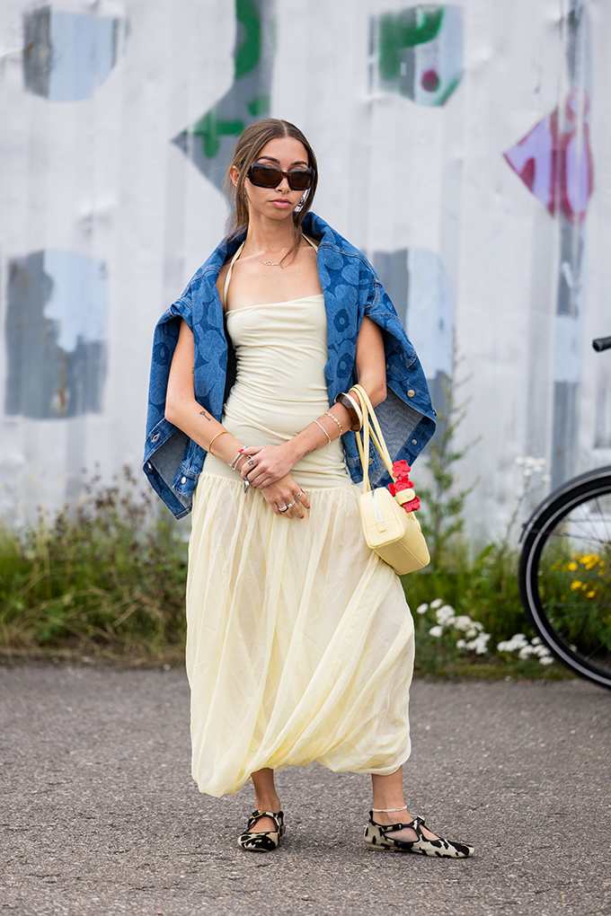 Frau trägt blaue Jeansjacke über den Schultern, kombiniert zu einem Kleid in Butter Yellow-Farbton