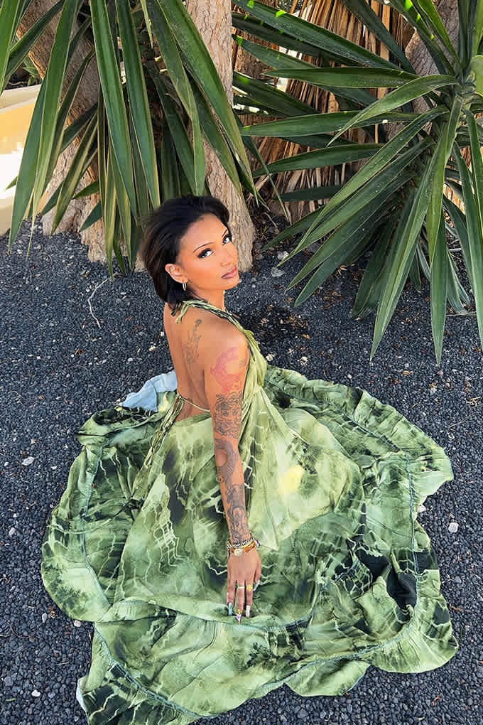 Influencerin Jess @25o.clock steht in grün-wallendem Kleid neben Palme