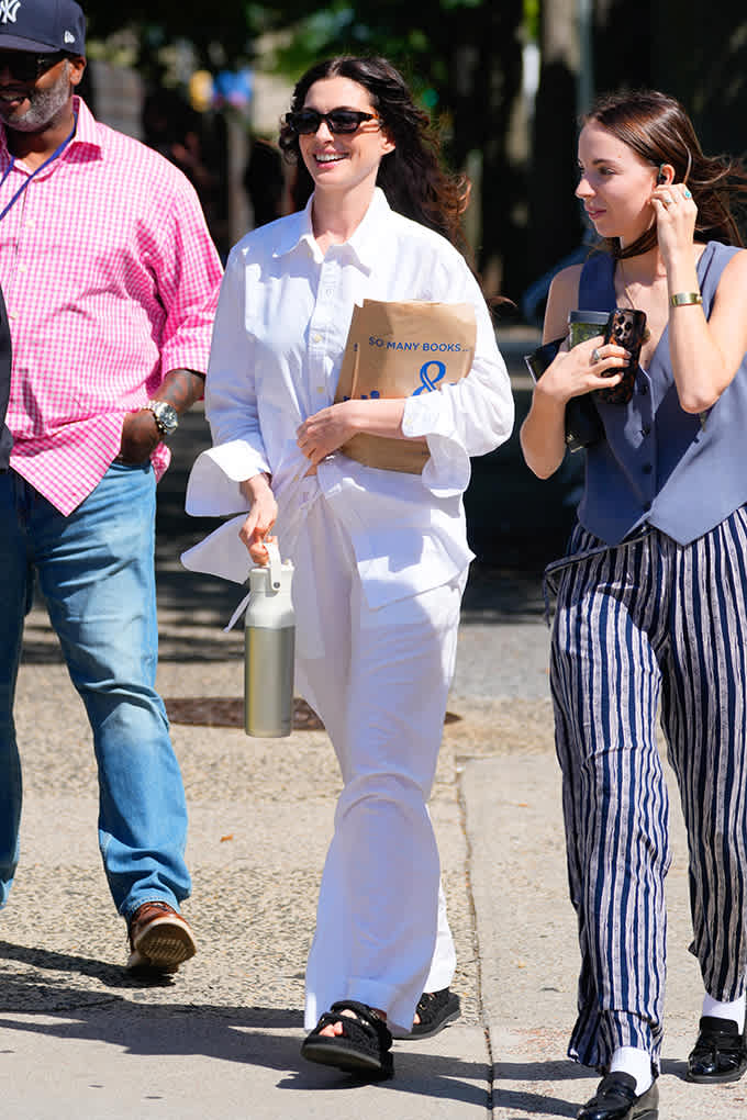 Schauspielerin Anne Hathaway spaziert in weißem Oversize-Hemd mit Wide Pants und Slides