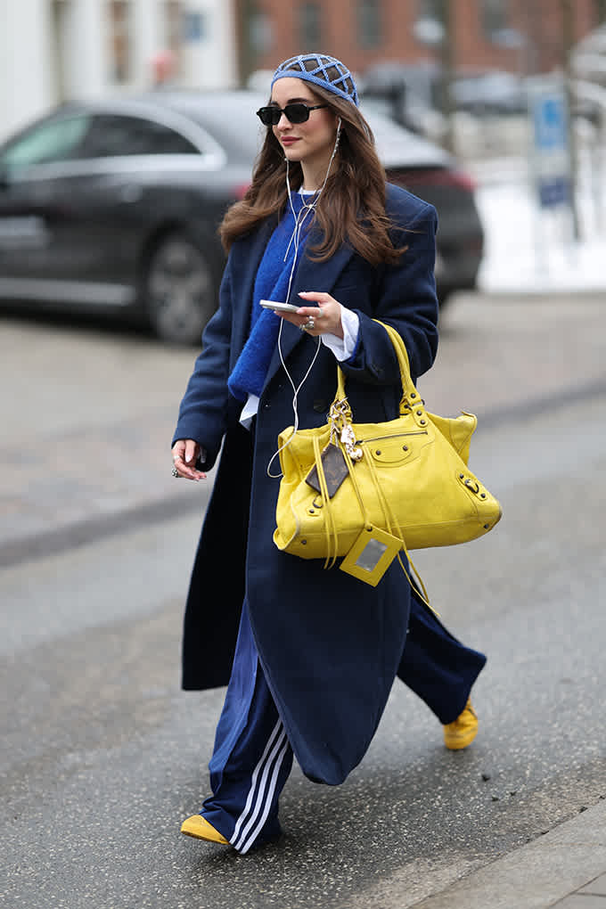 Frau in lässigem Jogging-Outfit der Marke adidas, mit knallgelber Handtasche