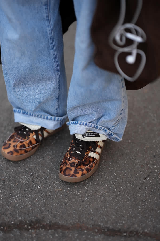 Person trägt Jeanshose in Kombination mit adidas-Sneakern in Leopard-Print