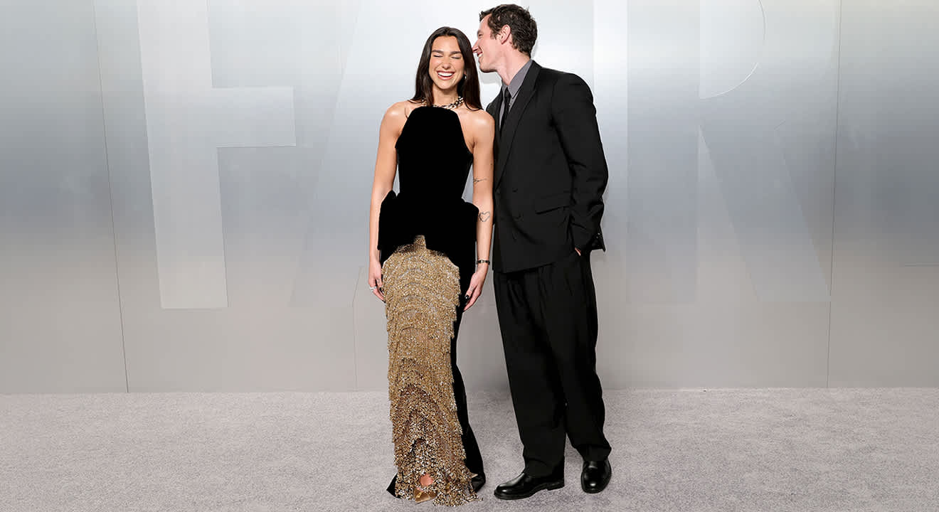 Dua Lipa und Callum Turner stehen in festlichen Outfits nebeneinander