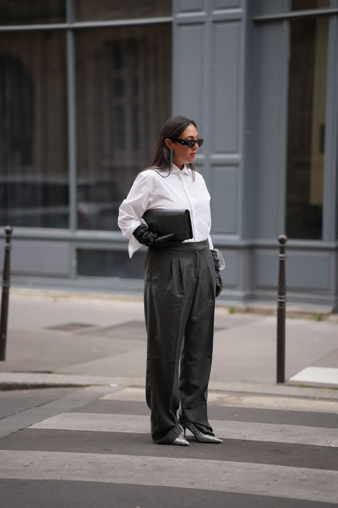 Frau in Business Look, trägt weißes Top mit grauer Suit-Hose und silbernen Heels