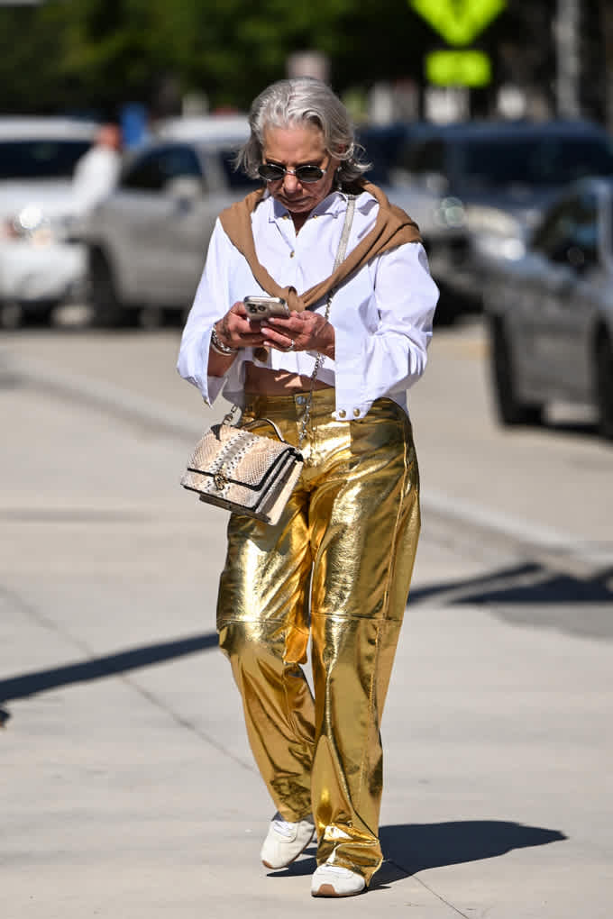 Frau trägt weiße Bluse in Kombination mit goldenen Metallic-Pants