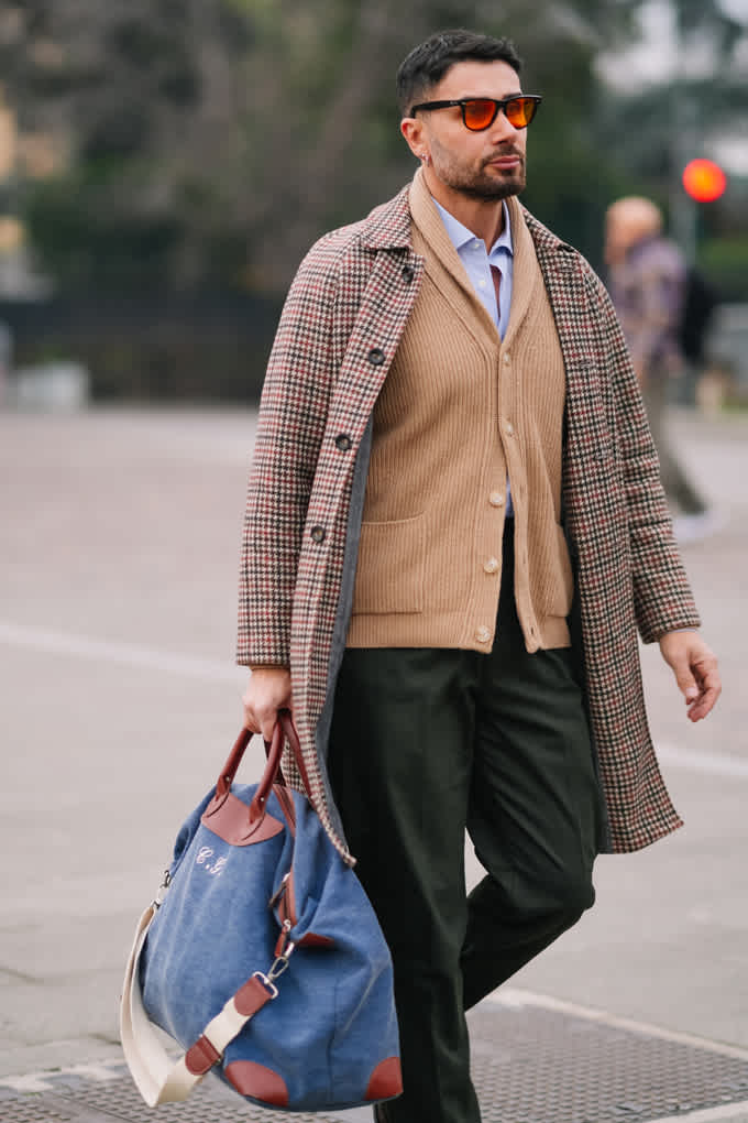 Mann auf der Pitti Uomo 2026, trägt grauen Caro-Mantel mit Cardigan