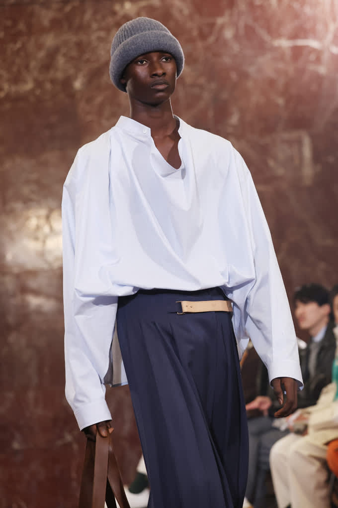 Schwarzes Model mit weißem Oversize-Shirt und grauem Beanie auf der Pitti Uomo 2026