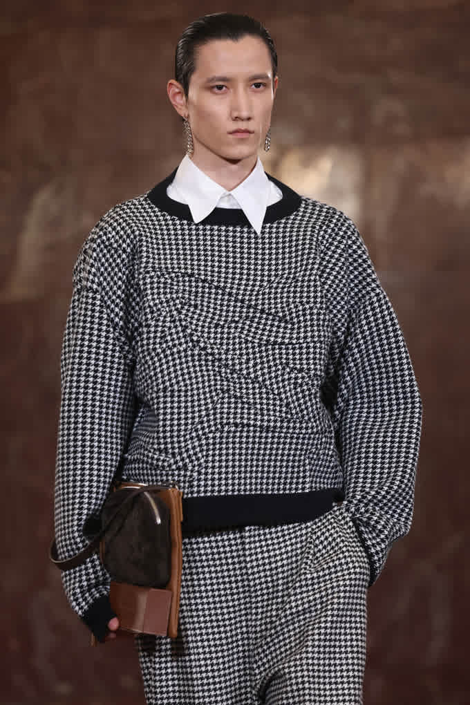 Männliches Model trägt Pullover und Hose im Hahnentritt-Muster