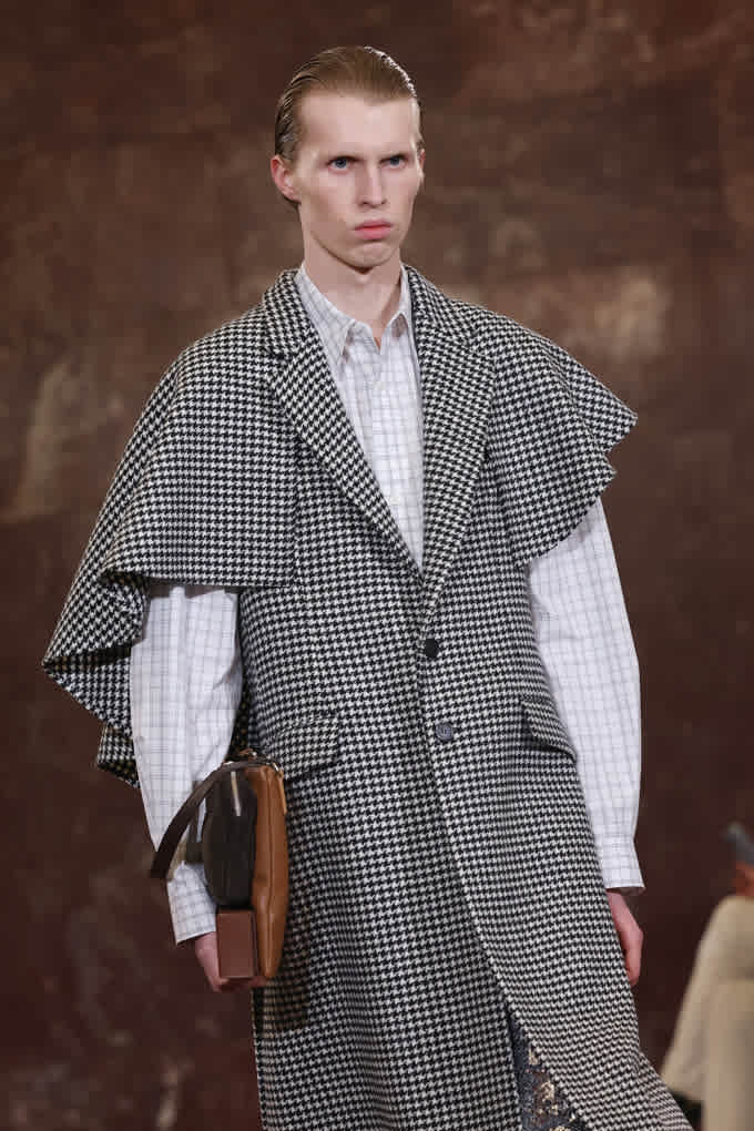 Mann trägt Cape-ähnliche Silhouette aus Hahnentritt, darunter ein klassisches Hemd