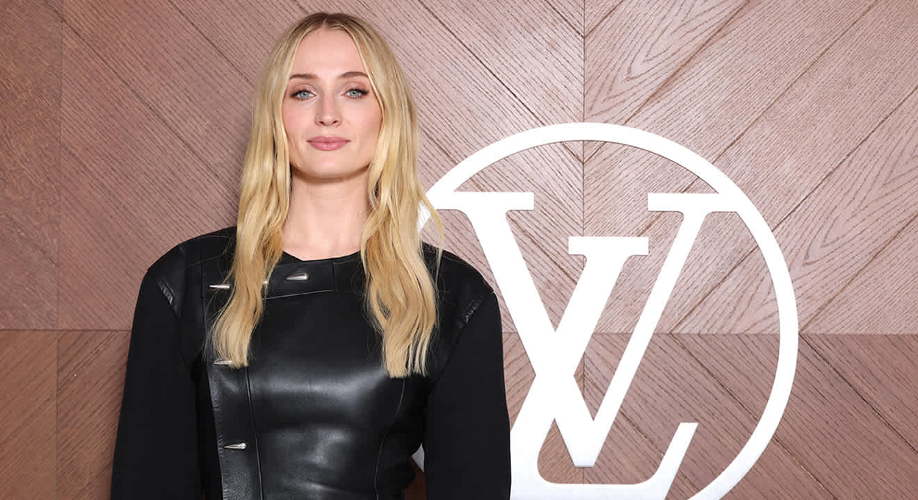 Sophie Turner in schwarzem Dress vor Logo-Wand