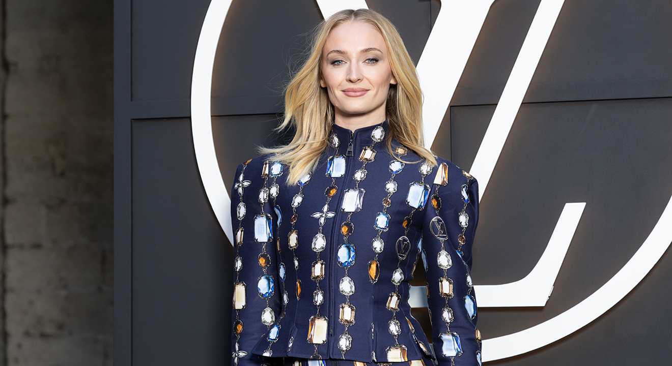 Sophie Turner in blauem Patch-Dress vor großem "Louis Vuitton-Zeichen"