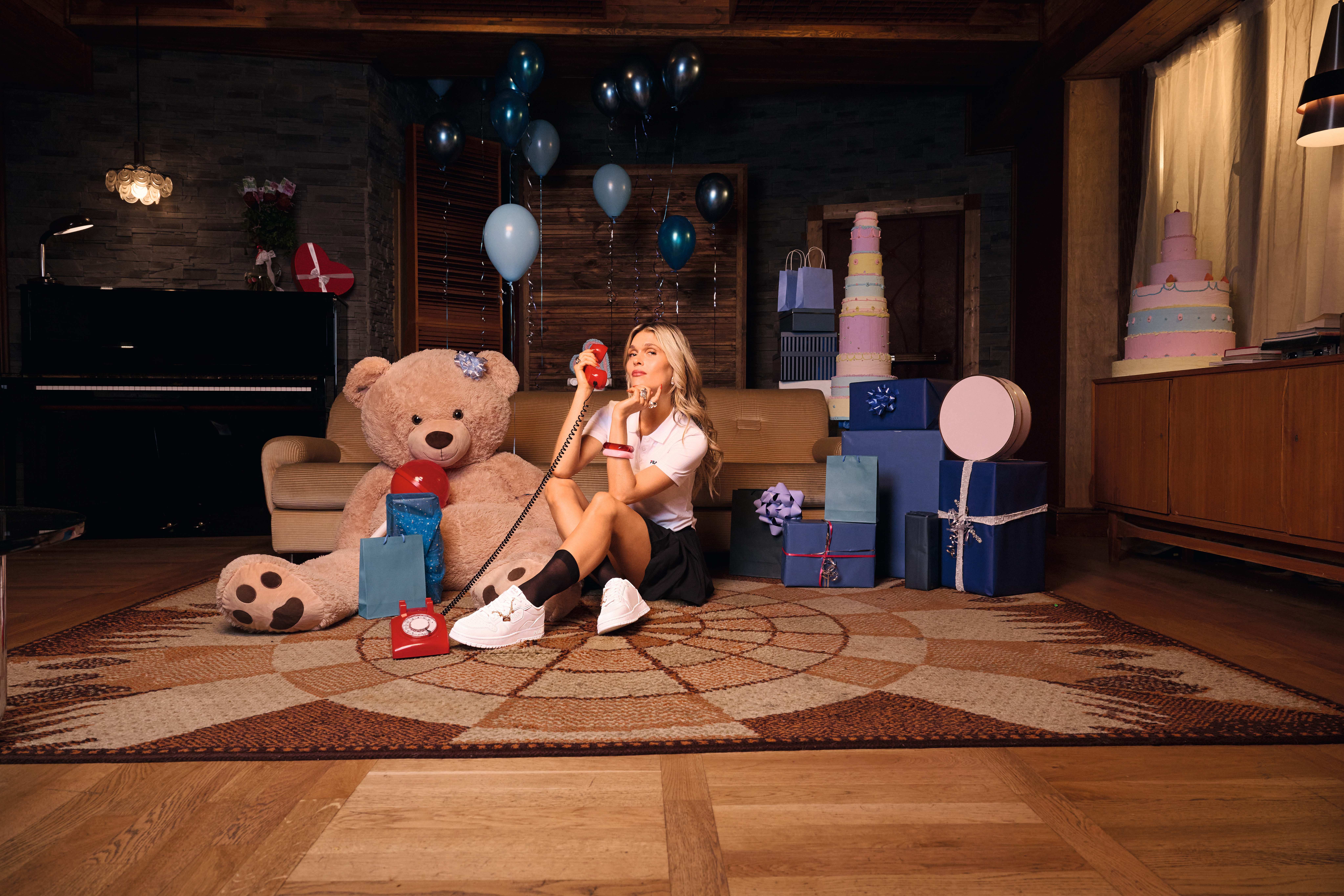 Sängerin anaïs sitzt auf Teppichboden, trägt sportliches Outfit, hält rotes Schnur-Telefon in der Hand