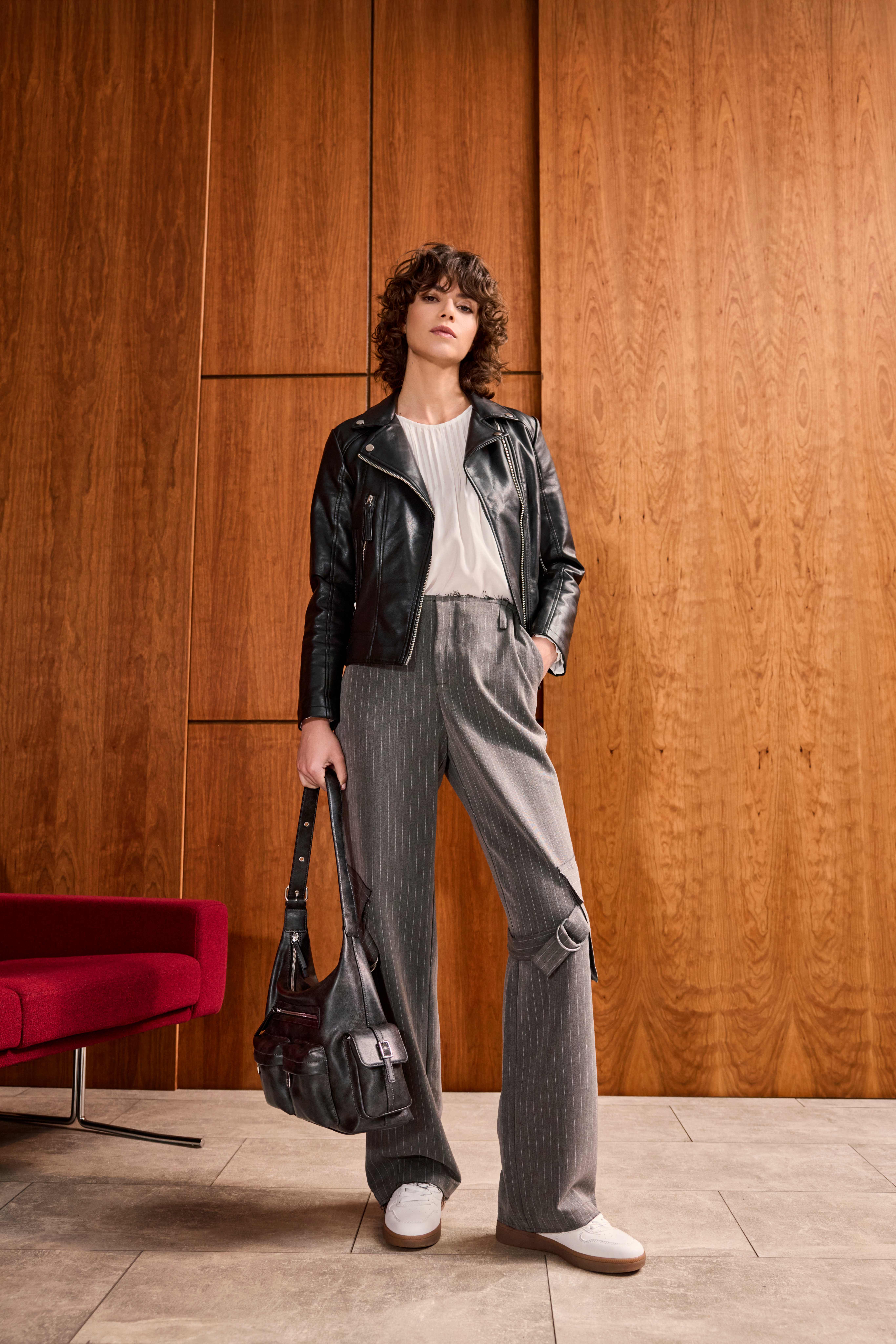 Frau mit Biker-Lederjacke, Pinstripe-Pants und weißen Sneakern 