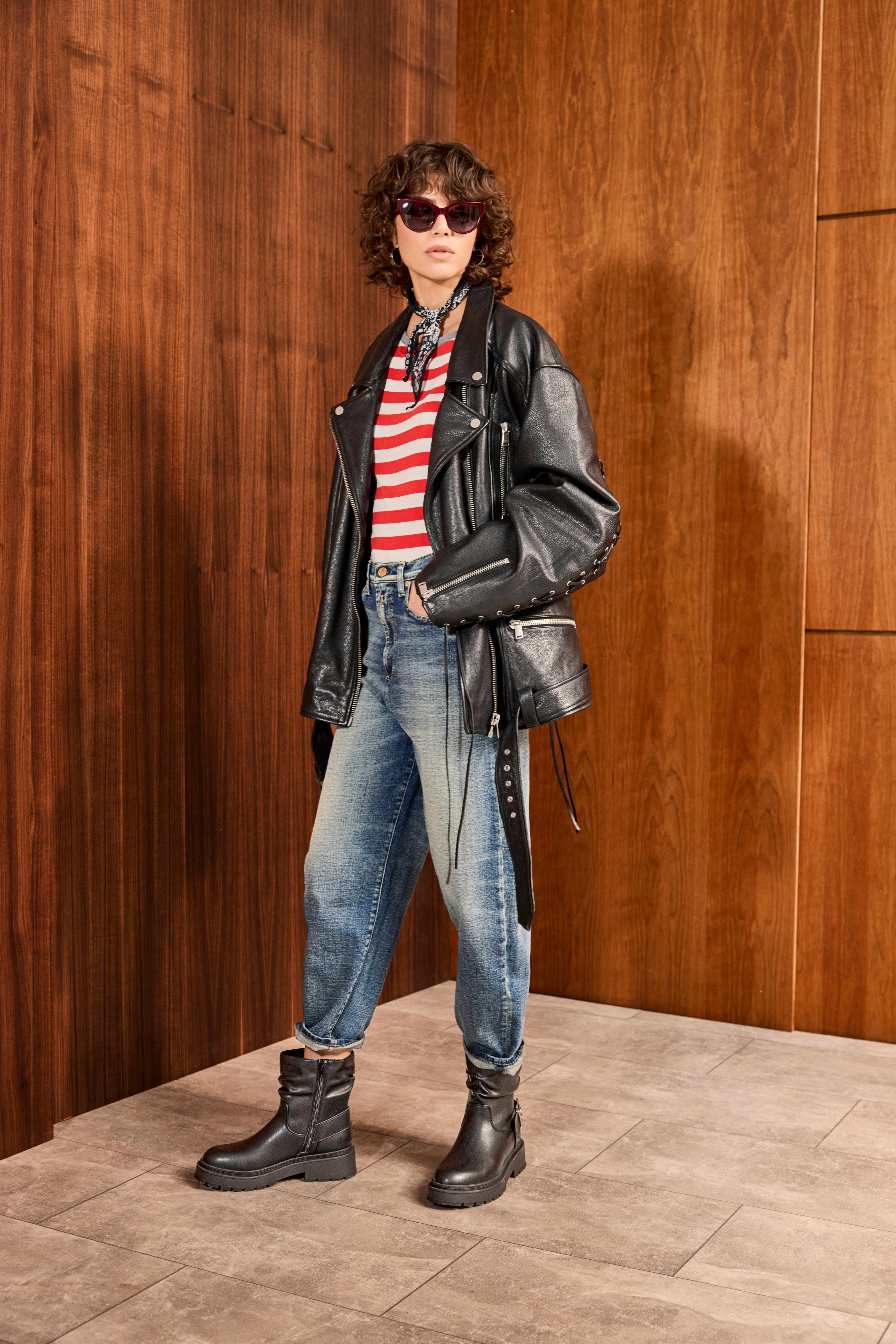 Frau posiert in Outfit mit schwarzer Lederjacke, rot-weiß gestreiftem Shirt und Washed-Out Barrel-Jeans