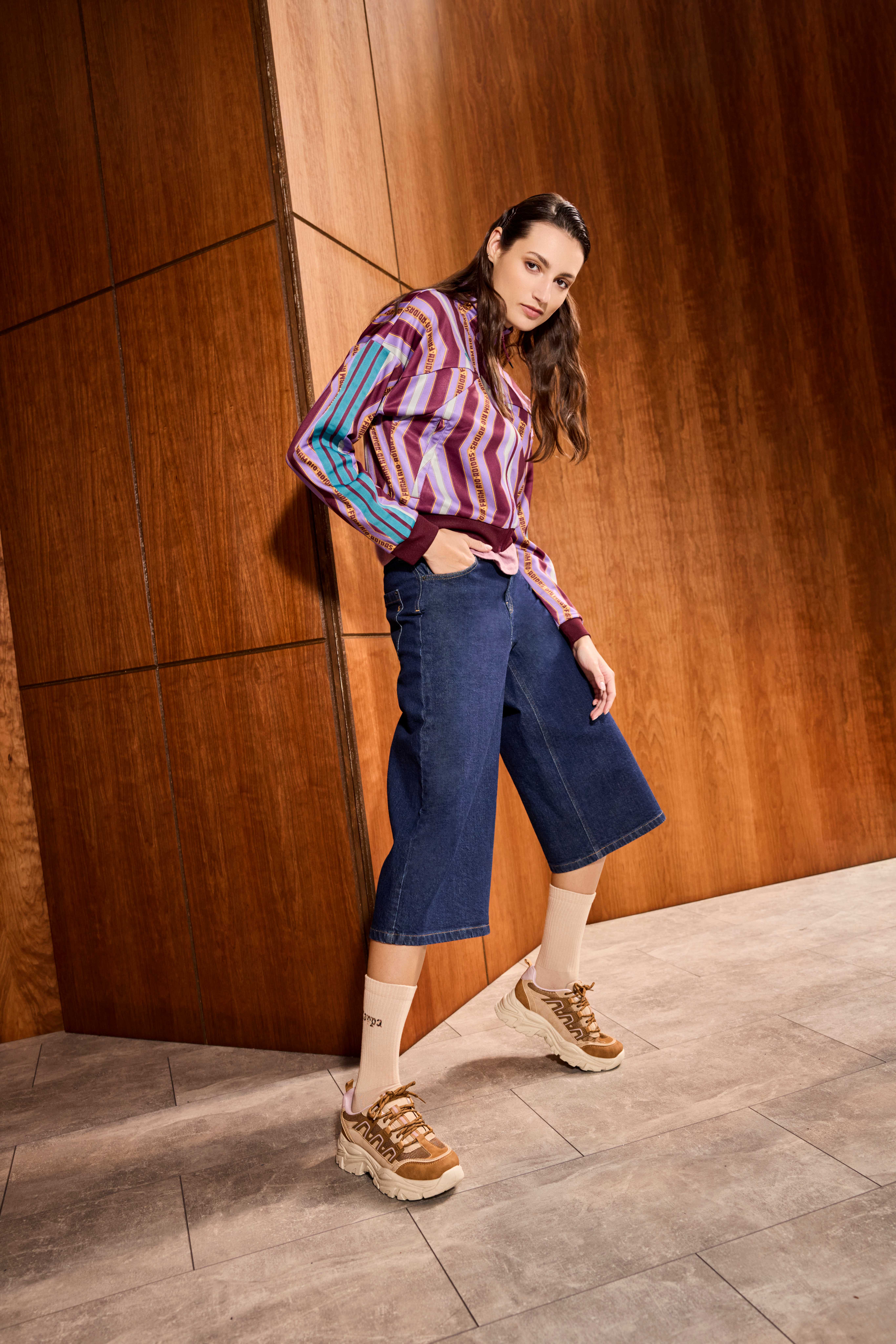 Frau in Retro-Design-Blouson mit Bermuda-Shorts und Dad Sneakern