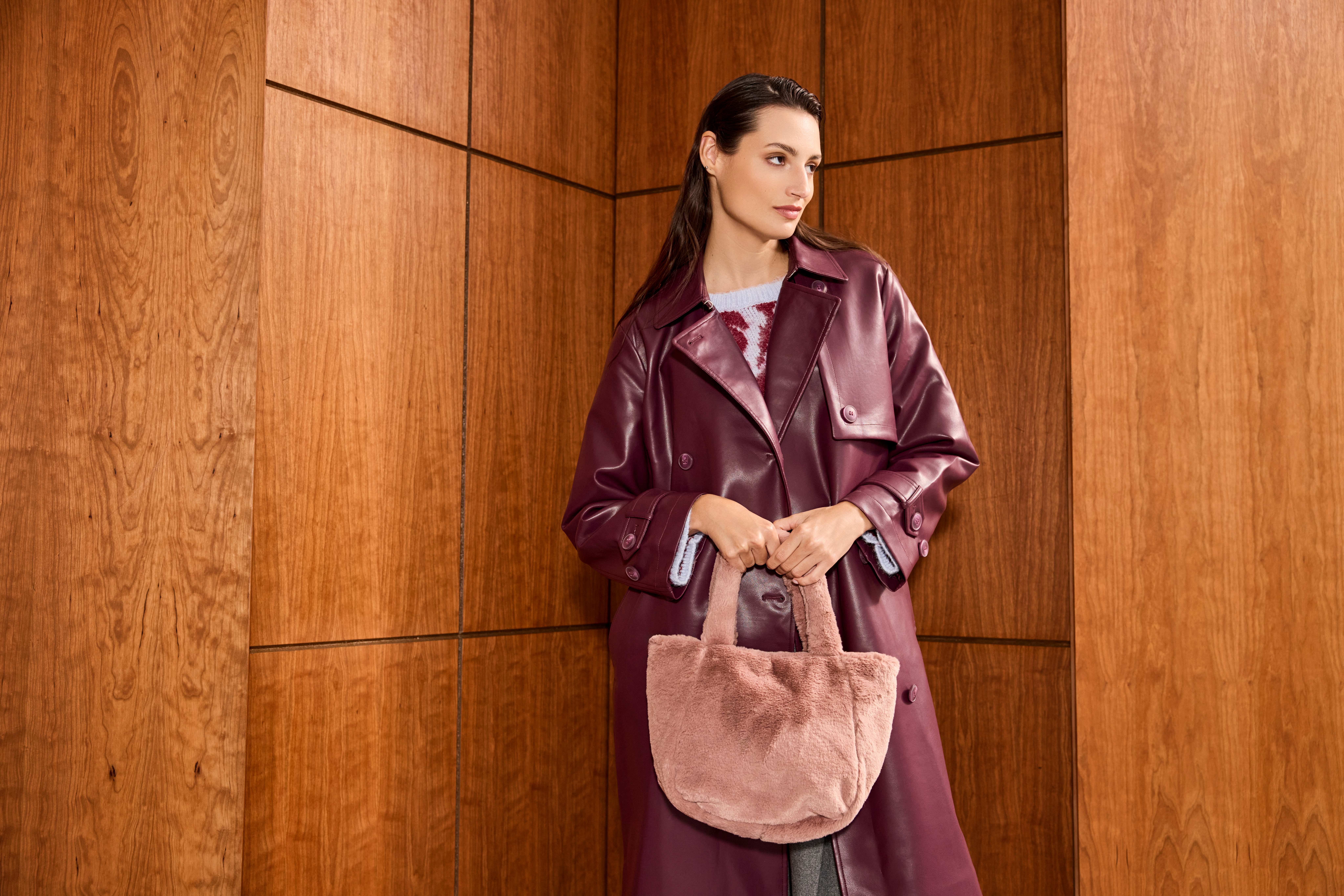 Frau in liafarbenem Suit trägt pinke Faux Fur-Handtasche