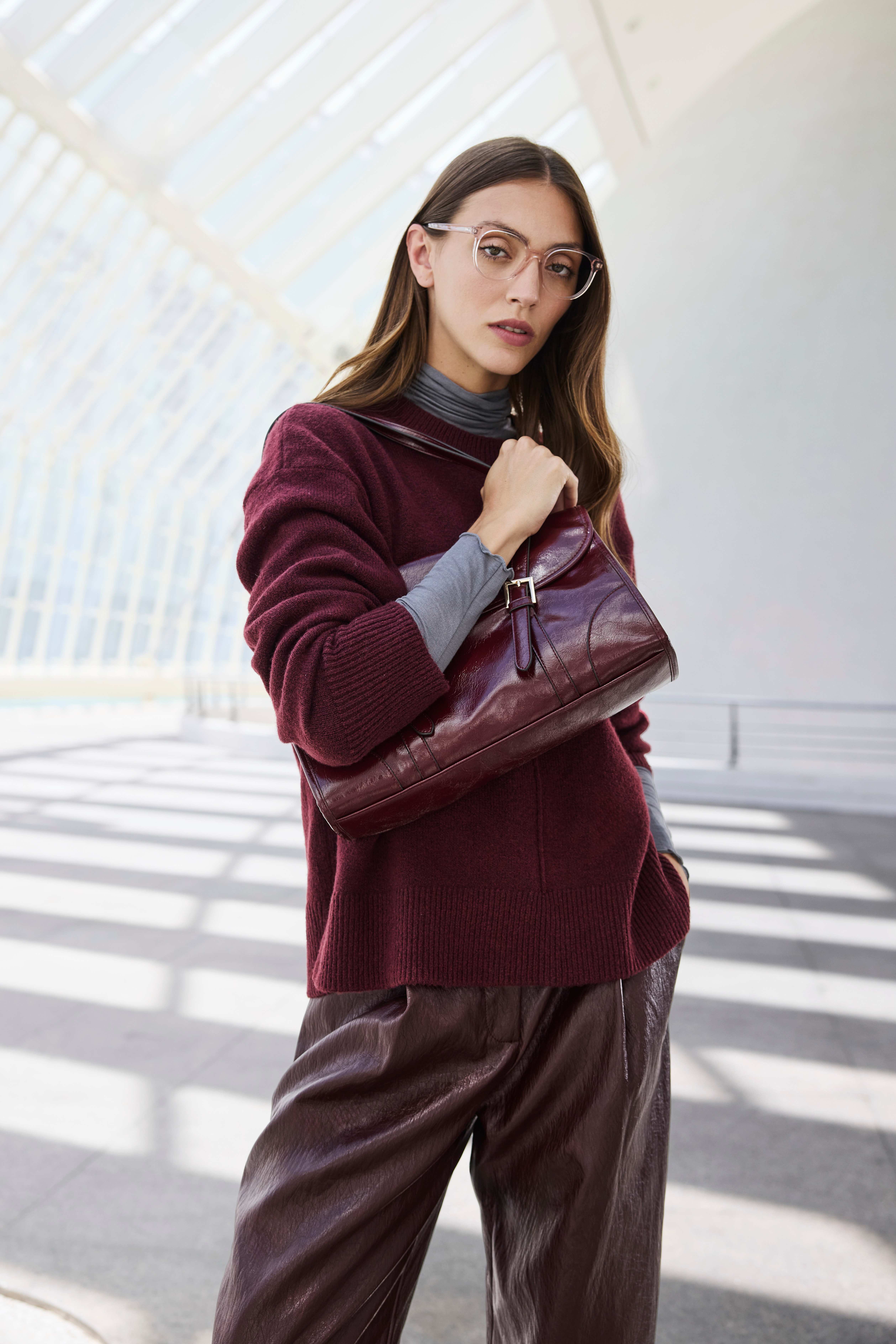 Frau in weinrotem Pullover, kombiniert mit passender Hose und Handtasche