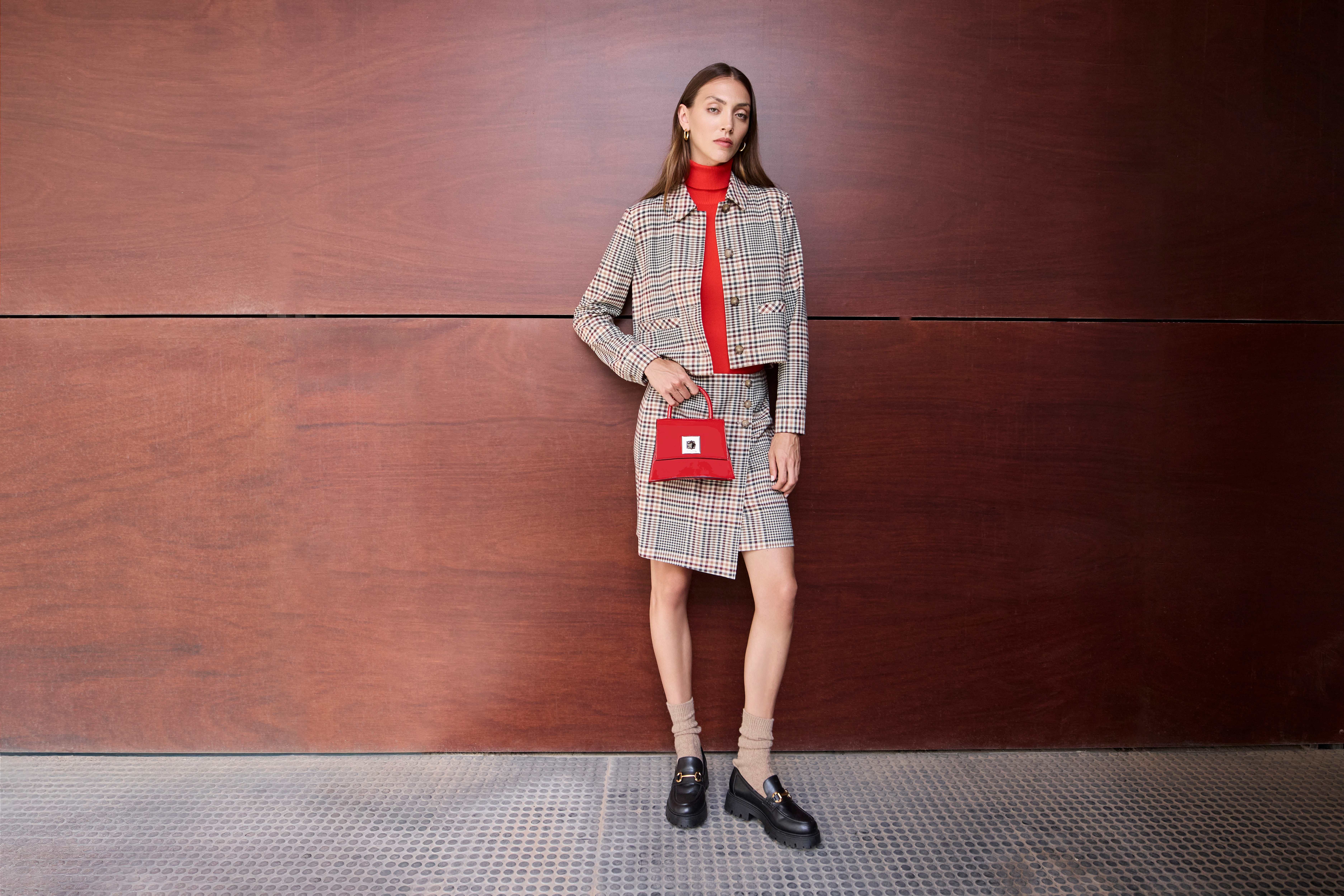 Frau in grauem Blazer mit Skirt und rotem Turtleneck im Corporate Core-Chic