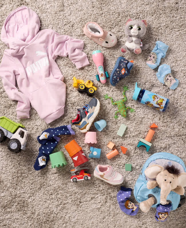 Top-Down-Ansicht von Kinder-Kleidung, Spielzeug & Accessoires auf einem Teppich